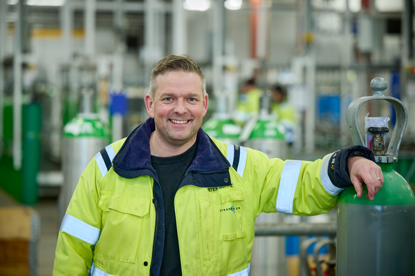 Glade medarbejdere på fabrik mellem flasker snakker om arbejdsplads. Sikkert arbejde i gas industri. 